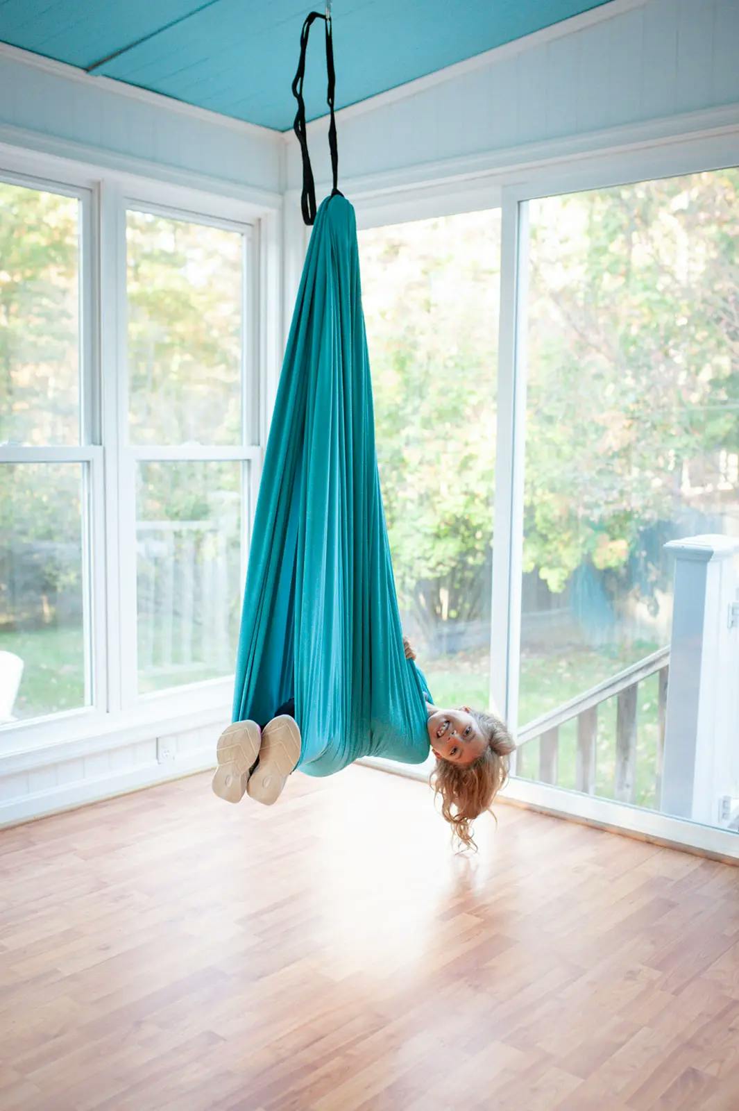 A child laying in an Ocean blue sensory swing by 21st Sensory