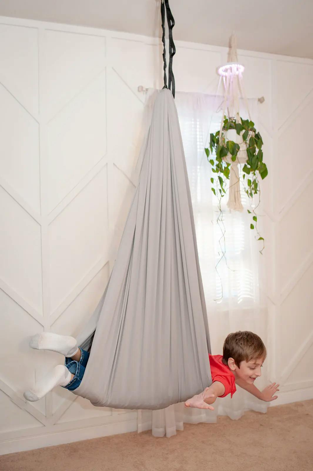 A child simulating flying in a Pebble sensory swing by 21st Sensory